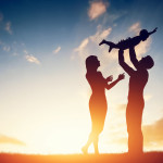 Happy family together, parents with their little child at sunset