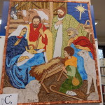 A C betlehem színes textildarabokból összehímzett képen ábrázolja a kis Jézus születését.